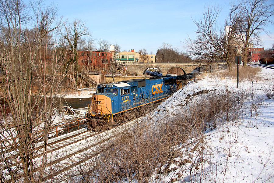 A westbound manifest freight passes through Kent with the stoned arch bridge carrying Main Street over the Cuyahoga River and the CSX New Castle Subdivision in the background.