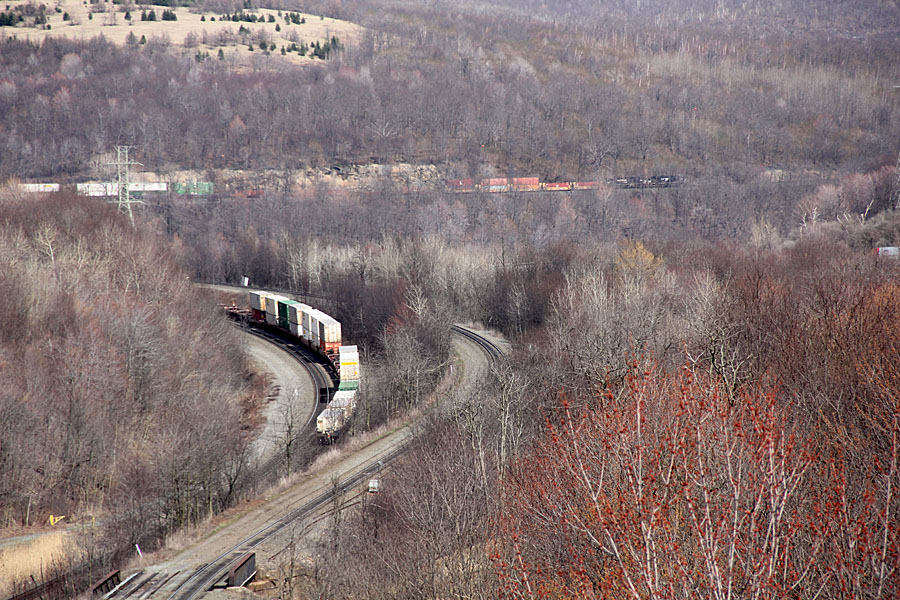 The rear of the eastbound stacker in the foreground with the head end of the same train visible in the upper right hand corner.