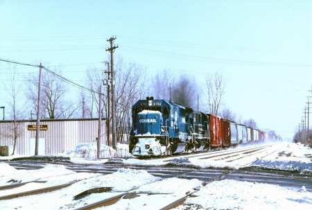 Conrail westbound freight is about to cross Front Street while passing Berea Hardware behind SD50 No. 6782.