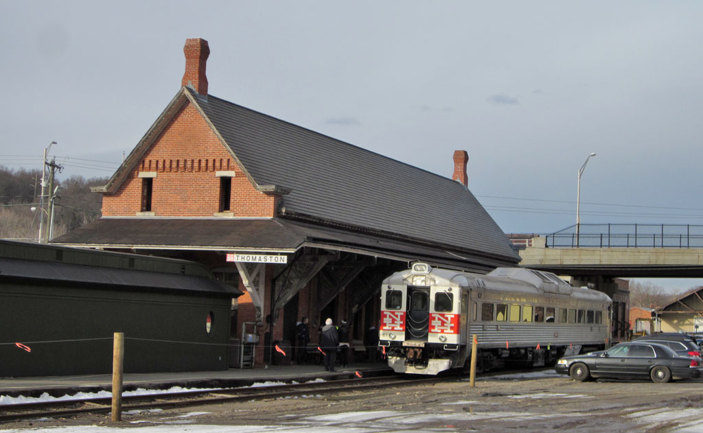 A Rail Diesel Car wearing New Haven markings pauses at the station in Thomaston, Connecticut.